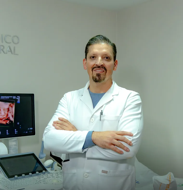 El Dr. Juan Dorian Tenorio Narváez, de brazos cruzados, junto al ecógrafo de su consultorio en el Centro Médico Mujer Integral.
